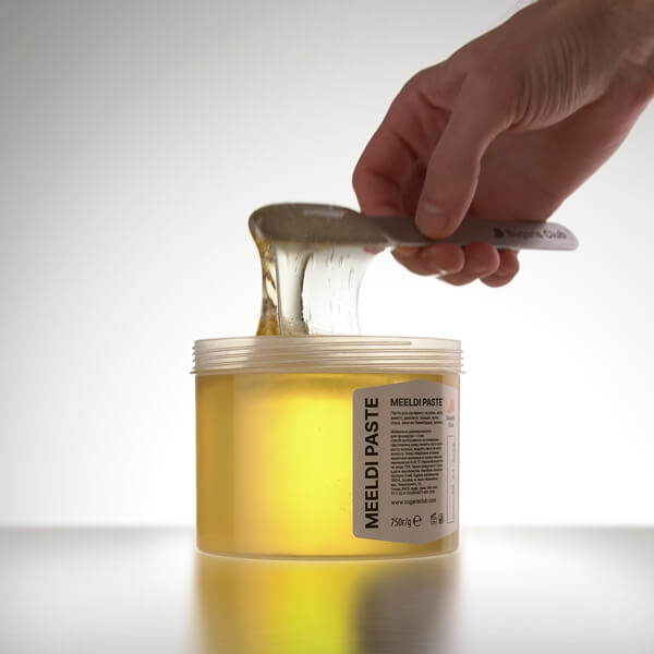 Чоловік набирає пасту Meeldi 750 г від Sugaris Club за допомогою шпателя.